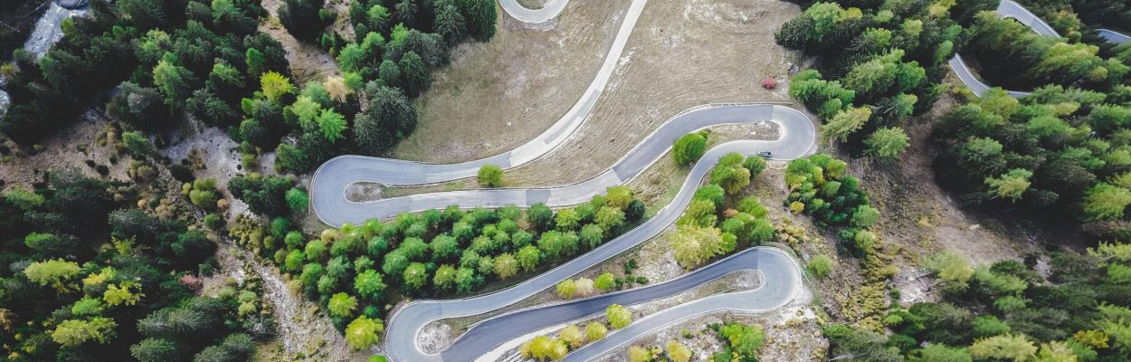 Scenic aerial view of a winding road through lush green forest, ideal for travel and nature themes.