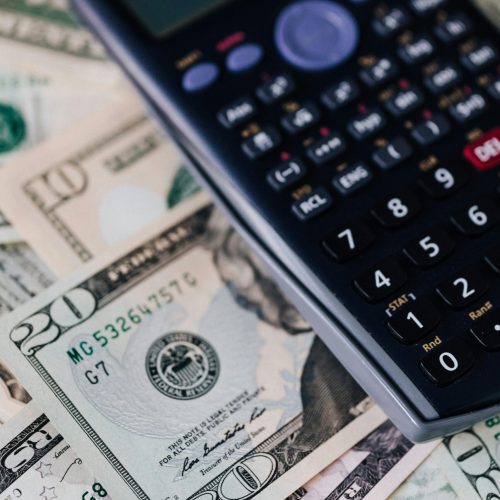 From above of calculator placed on paper banknotes of American dollars on table